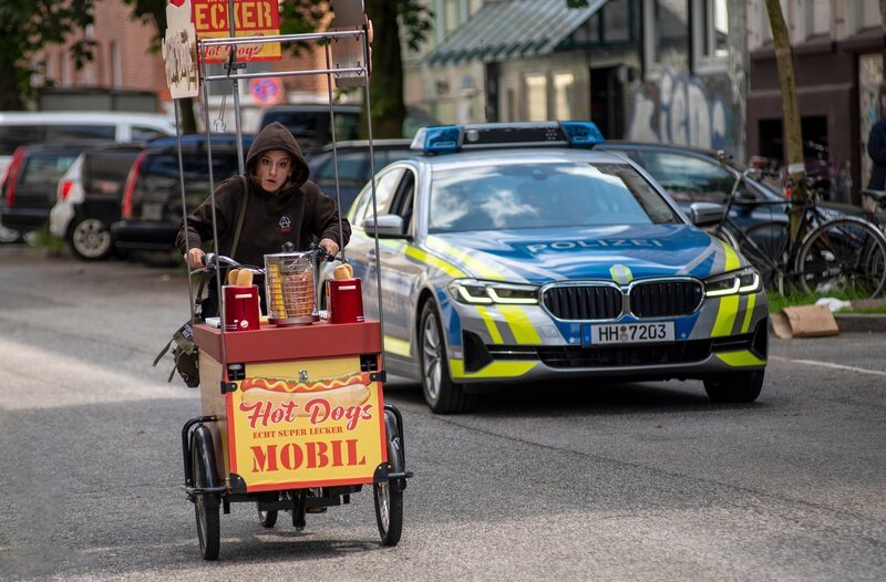 Um möglichst schnell zu ihrem entführten Hund zu kommen, stiehlt Nuri Hakimi (Meryem Ebru Öz, l.) ausgerechnet ein Hotdog-Verkaufsfahrrad und stoppt nicht einmal, als die Polizei sie dazu auffordert. – Bild: ARD/​Thorsten Jander