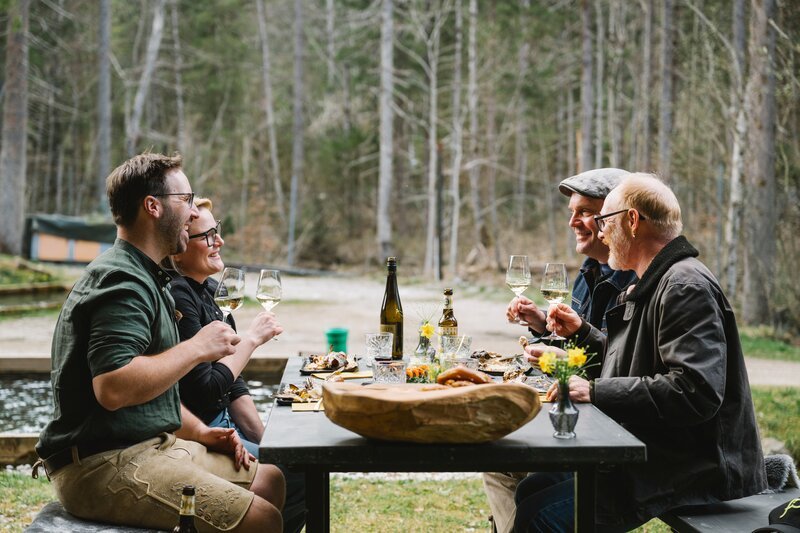 Von links: Dominik Blees (Fischzüchter), Manuela Merk (Fischzüchterin), Sebastian Bezzel und Simon Schwarz beim gemeinsamen Essen. – Bild: Schelke Bonnetsmüller /​ BR/​Film Five GmbH