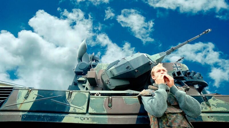Christina (Christian Clauß) vor einem Panzer. – Bild: MDR/​Andrej Bavschenkov