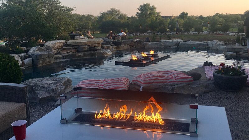 A tabletop, glass enclosed fire pit sits as a focal point within the patio furniture, tying the pool into the landscape by including fire in both. – Bild: HGTV /​ Scripps (Focus) /​ Discovery Communications