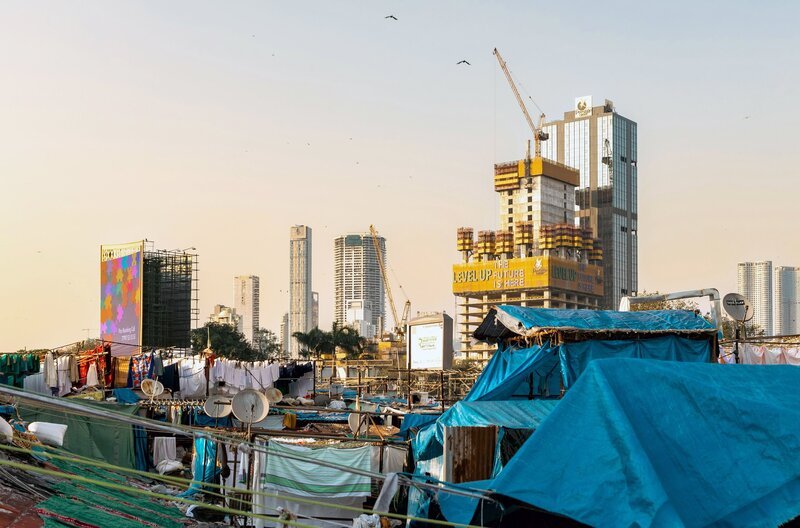 Schicke Hochhäuser neben Slums: Während die Mittelschicht in Indien wächst, bleiben große Teile der Bevölkerung abgehängt. – Bild: Zoshua Colah/​Unsplash