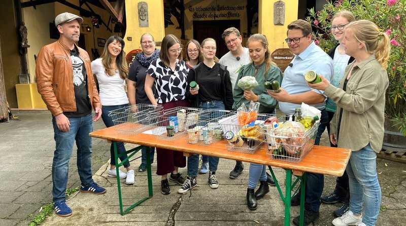 Doc Esser (l) und Ernährungsexpertin Dr. Jon Chim Bai-Habelski (2.v.l.) zeigen neun Rettungshelfer*innen aus Bad Honnef, worauf es bei der Auswahl von Lebensmitteln ankommt. – Bild: WDR/​Solis TV