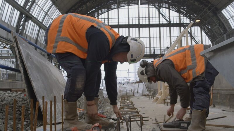 Jordy und Ivo arbeiten gemeinsam daran, Metallteile im Betonboden zu befestigen. – Bild: National Geographic
