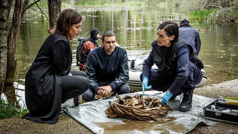In einem See wurden die restlichen Gebeine von Viktor Eklund geborgen. Alexandra Beijer (Jennie Silfverhjelm, l.) und Josef Eriksson (Martin Wallström) erfahren jedoch von Bergström (Ĺsa Karlin, r.), dass die Knochen erst vor Kurzem in dem See versenkt wurden. – Bild: ZDF