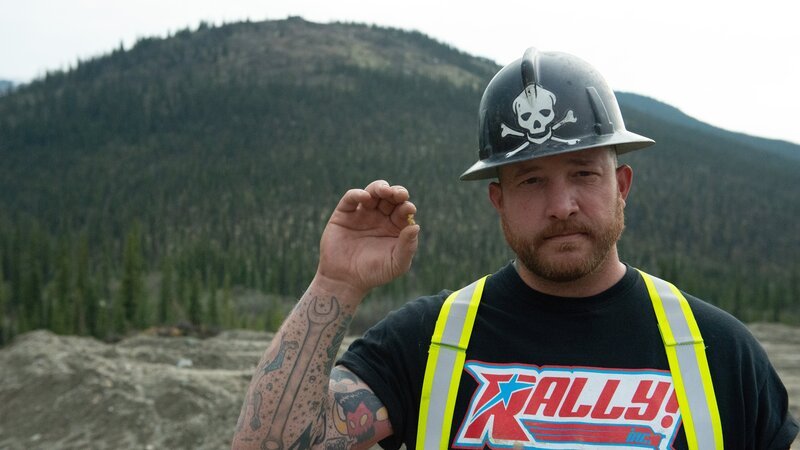 Rick holding a Golden Nugget looking directly into camera with landscape – Bild: Raw TV