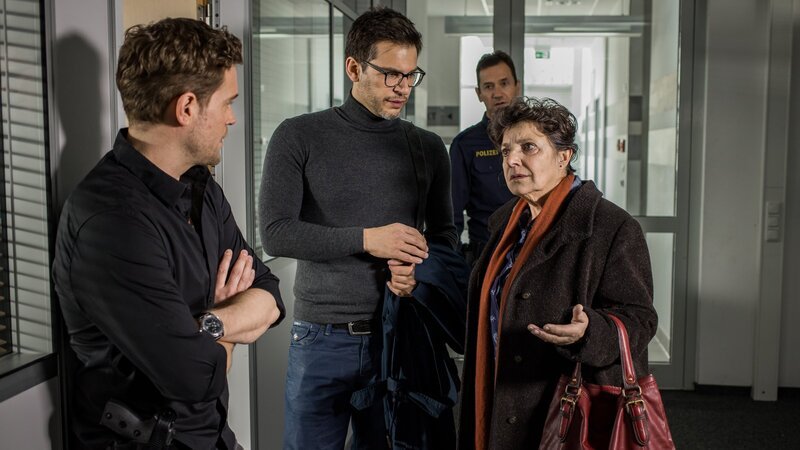 Traudl Presinsky (Monika Baumgartner, r.) kommt ins SOKO-Büro, wo sie Dominik Morgenstern (Joscha Kiefer, l.) und Dr. Weissenböck (Florian Odendahl, M.) antrifft. – Bild: ZDF