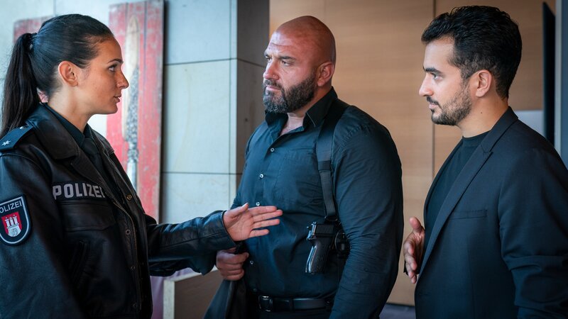 Pinar (Aybi Era, l.) zeigt ihrem Bruder Malik (Timo Fakhravar, r.), dass auch der Bodyguard (Komparse) der Aslans sie nicht davon abhalten kann, unbequeme Fragen zu stellen. – Bild: Boris Laewen /​ ZDF