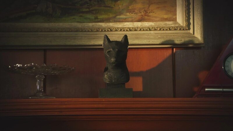 Büste der altägyptischen Göttin Bastet in Form einer Katze, platziert auf einer Holzkommode vor einem gerahmten Kunstgemälde. – Bild: The Movie Database (TMDb)