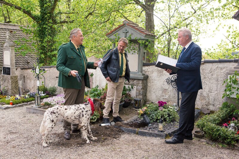Hund Amarillo hat auf dem Friedhof gewütet und an einer Grabstätte gebuddelt: Hubert (Christian Tramitz, M.) und Girwidz (Michael Brandner, l.) müssen es dem Friedhofswärter (Komparse, r.) erklären. – Bild: TMG /​ Kai Neunert