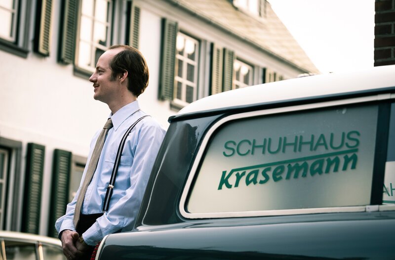 Benno Krasemann (Merlin Sandmeyer) parkt sein Auto vor seinem Schuhladen. – Bild: WDR/​UFA Fiction/​Martin Valentin Menke