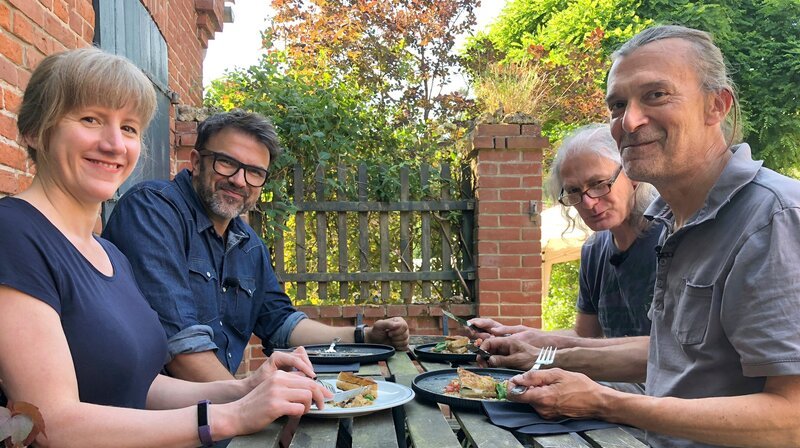 Guten Appetit! Tarik Rose bei den Gülzer Geißen-Bauern Uli und Rudi samt Australischer Praktikantin. – Bild: NDR/​Svenja Halberstadt