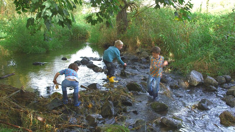 Gemeinsam wollen die drei das Wasser zu einem kleinen See stauen, um auszuprobieren, wie gut das neue Boot schwimmt. – Bild: KiKA