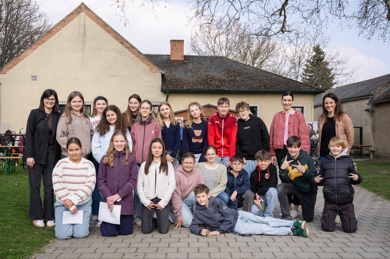 Die Schülerinnen und Schüler der Mittelschule Andau im Burgenland haben einen Dorftratsch organisiert und lesen den Besuchern selbstgeschriebene Geschichten über ihre Zeit ohne Handy vor. (Lisa Gadenstätter, hinter, r.) – Bild: ORF/​Stefan Vucsina