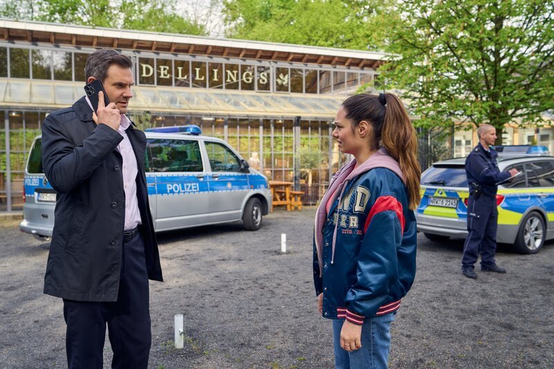Im „Haus Delling“, einer Öl- und Gewürzhandlung, hat es einen Todschlag gegeben. Kommissare Amira Mahdi (Aylin Ravanyar, r.) und Jonas Fischer (Lukas Piloty, l.) treffen sich am Tatort, um die Ermittlungen aufzunehmen. Doch Jonas muss noch etwas Wichtigeres klären. (Komparse im Bild) – Bild: Frank Dicks /​ ZDF und Frank Dicks
