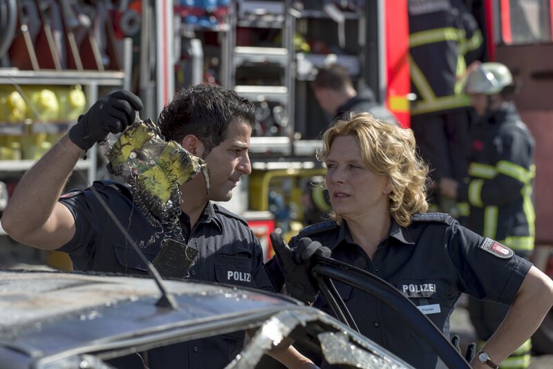 Claudia (Janette Rauch) und Tarik (Serhat Cokgezen) wurden zu einem brennenden Fahrzeug gerufen. Nachdem die Feuerwehr den Wagen gelöscht hat, findet Tarik den Brandsatz mit Zeitzünder. – Bild: ZDF/​Boris Laewen (bola)