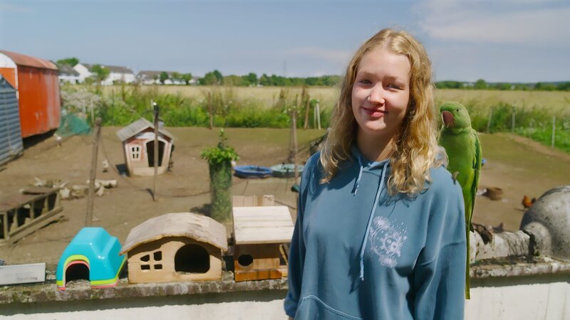 Nina beim Besuch der Vogelauffangstation mit einem geretteten Papagei. – Bild: BR/​Text und Bild Medienproduktion GmbH & Co. KG/​Marcella Müller