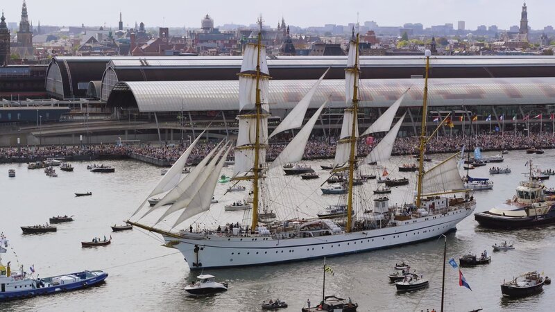 Luftaufnahme der Ankunft des Mautschiffs „Amsterdam“ während der Sail 2025, im Hintergrund der Amsterdamer Hauptbahnhof. – Bild: National Geographic