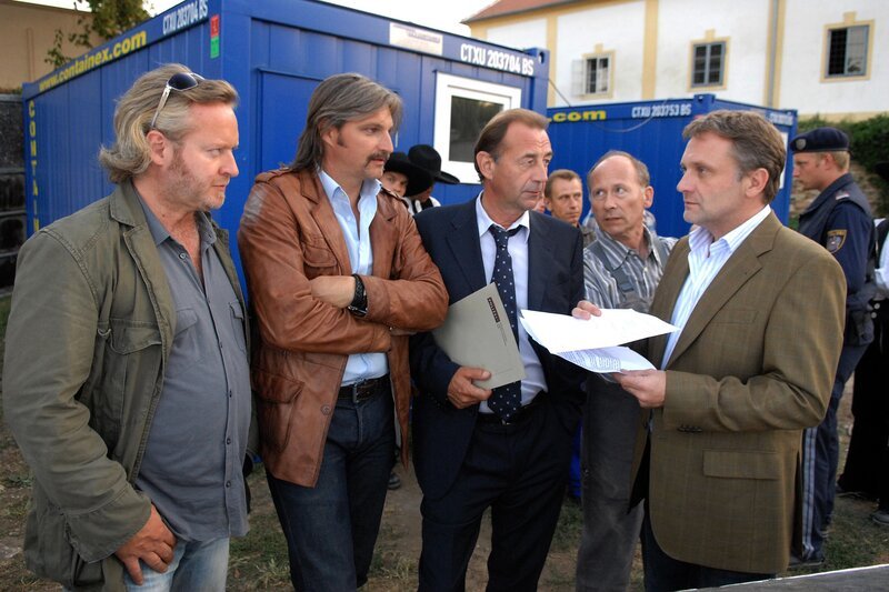 Helmuth Nowak (Gregor Seberg, l.), sein Kollege Carl Ribarski (Stefan Jürgens, 2.v.l.) und deren Chef Oberst Otto Dirnberger (Dietrich Siegl, M.) befragen auf einer Baustelle den Steinmetz Josef Kohlmayr (Peter Faerber, 3.v.r.) und dessen Chef Jochen Miklau (Bernhard Schir, 2.v.r.) zum Tod eines Wandergesellen. – Bild: ZDF/​Hubert Mican