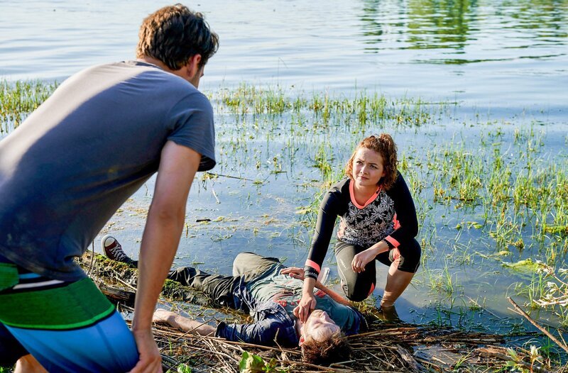 Das morgendliche Stand-up-Paddling von Jakob Frings (Max König, l.) und Julia Demmler (Wendy Güntensperger, r.) in der Liebesbucht findet ein jähes Ende, als Julia einen leblosen Körper am Ufer des Bodensees entdeckt. – Bild: ORF/​Bavaria/​ARD/​SWR/​Nicolas Gradicsky