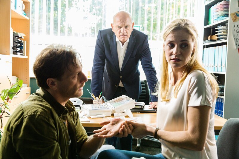 Stefan (Hendrik Duryn, l.) verarztet Karins (Jessica Ginkel) Wunde. Direktor Rose (Uli Gebauer) will sich ab nun mehr Zeit für sich nehmen. – Bild: TVNOW /​ Frank Dicks /​ Sony Pictures FFP