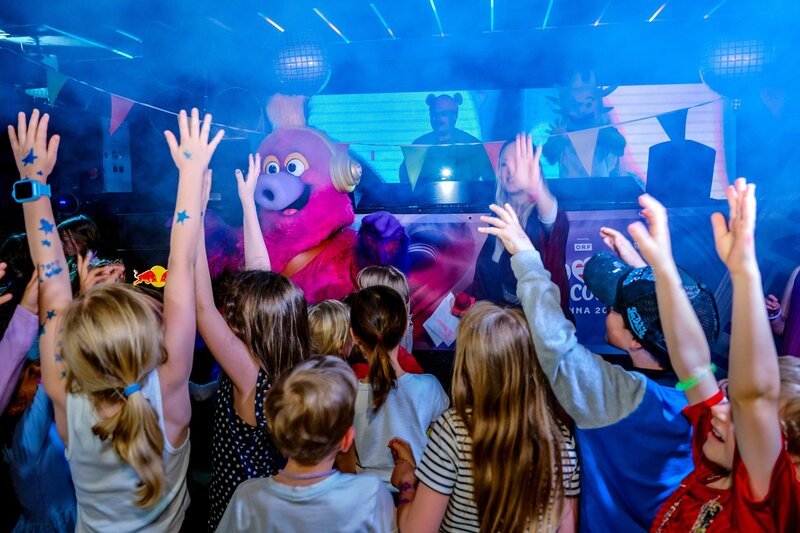 Lilian Klebow zu Besuch bei der großen Kinderdisco, wo Kinder gemeinsam mit ESC-Maskottchen Auri tanzen. – Bild: ORF/​Klaus Titzer