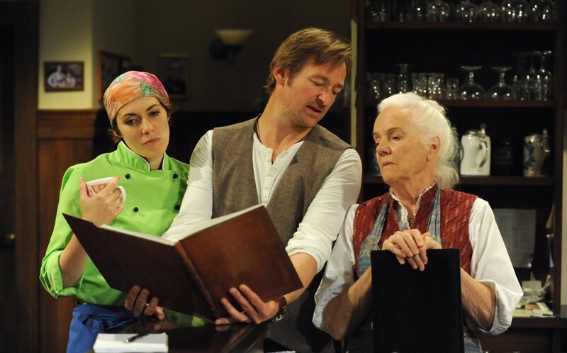 Theres beschwert sich bei Fanny und Gregor über die Karikatur. Von links: Fanny Lechner (Katrin Lux), Gregor Brunner (Holger M. Wilhelm) und Theresa Brunner (Ursula Erber). – Bild: BR/​Marco Orlando Pichler