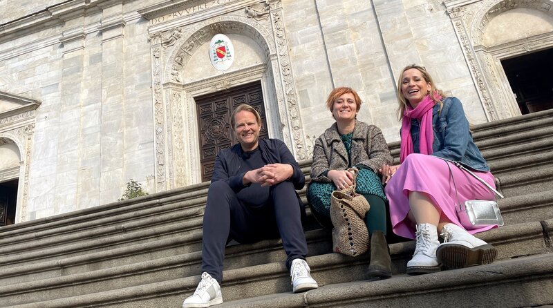 Spitzenkoch Björn Freitag (l) und Reiseexpertin Tamina Kallert in Turin auf den Stufen des Turiner Doms mit der Einheimischen Corinne Barsi (M). – Bild: WDR/​2bild GmbH/​Anja Tanas