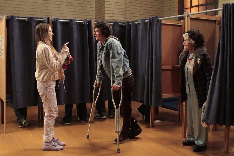 Nachdem Sue (Eden Sher, l.) Axl (Charlie McDermott, 2.v.l.) vor lauter Panik mit dem Auto über den Fuß gefahren ist, überredet er sie, ihn trotz ihrer Angst zum Wahllokal zu bringen, denn er darf das erste Mal wählen. Doch Sue will ihn nur in Begleitung von Tante Edie (Jeanette Miller, r.) fahren … – Bild: Warner Brothers