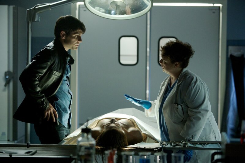 Von Dr. Harper (Sharon Sachs) erfährt Nick (David Giuntoli), dass das Opfer offenbar nicht an den Folgen des Unfalls gestorben ist, sondern erwürgt wurde. – Bild: Canal+