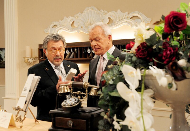 Werner (Dirk Galuba, r.) erkennt, dass Julius (Michele Oliveri, l.) als Portier überfordert ist. – Bild: ARD/​Ann Paur