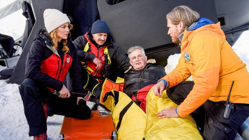 Die Bergretter Katharina (Luise Bähr, l.), Tobi (Markus Brandl, 2. v. l.) und Markus (Sebastian Ströbel, r.) sind froh, ihren Kollegen Michi (Robert Lohr, 2. v. r.) verletzt, aber lebend, gefunden zu haben. – Bild: ORF/​ZDF/​Barbara Bauriedl