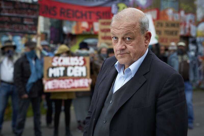 Georg Wilsberg (Leonard Lansink) unter falscher Identität als finanzstarker Investor bei einer Demonstration der Freihafen Initiative Münster. – Bild: ZDF und Guido Engels