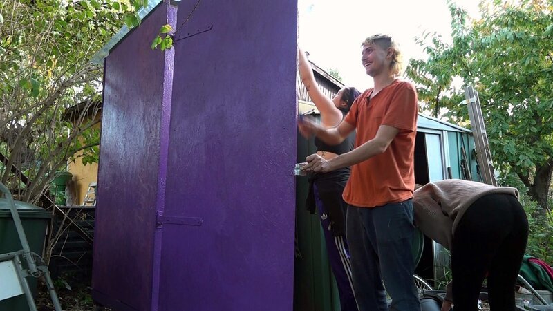 Malte setzt bei der Farbgebung des stillen Örtchens auf Akzente. Er verleiht der neuen Kompost-Toilette im Gemeinschaftsgarten eine auffällige lila Farbe. – Bild: RTLZWEI