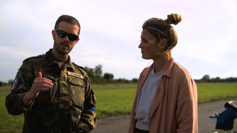 Bei einer NATO-Übung im belgischen Koksijde werden Angriffe mit ABC-Waffen simuliert. Hauptmann Florian (im Gespräch mit Reporterin Greta Buschhaus) leitet die Übung. – Bild: Benjamin Kahlmeyer