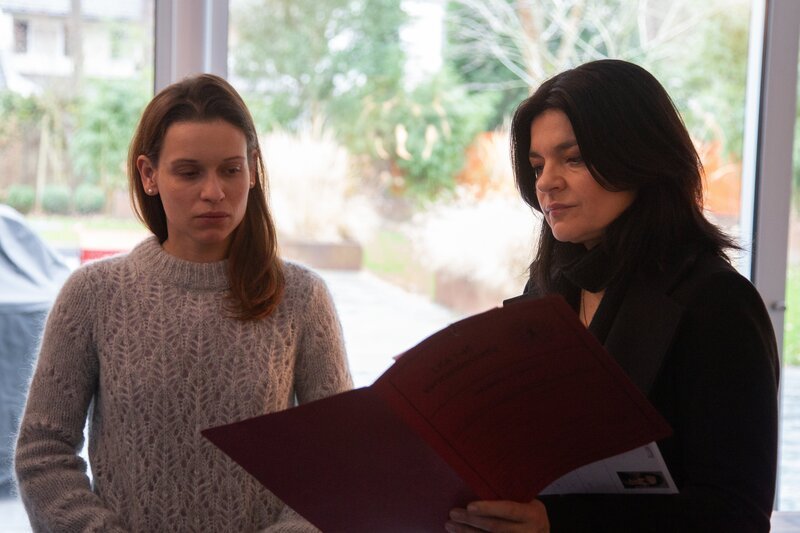 Mina (Jasmin Tabatabai, r.) zeigt Dore (Kristin Suckow, l.) Fotos von Bildern, die ihr Bruder Max gezeichnet hat. – Bild: ZDF und Delia Woehlert