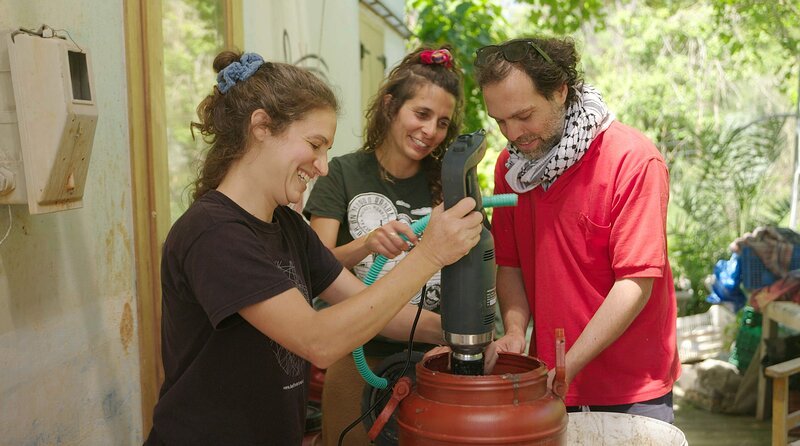 Auf einem Bauernhof bei Chania experimentieren Christina Lantzaki (mi.) und ihr Freund Nikos Gryspolakis (re.) mit Fischabfällen. Durch Zerkleinern und Fermentation entsteht daraus Fischöl, welches sie als wertvollen Pflanzendünger einsetzen und verkaufen. – Bild: NDR/​Eddy Zimmermann