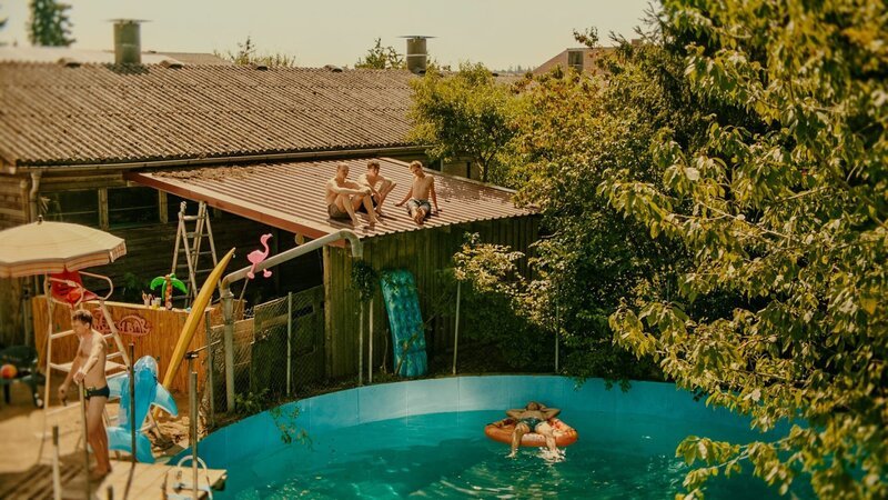 Die Jungs – Carlo (Jeremias Meyer, M.), BlaBla (Sebastian Jakob Doppelbauer, 2.v.l.) und Aydin (David Ali Rashed, 2.v.r.) chillen auf dem Vordach vor ihrem Pool, während Matze (Leon Hagen, r.) im Wasser liegt und Pius (Valentin Erb, l.) am Einstieg steht. – Bild: Conrad Lobst /​ ZDF