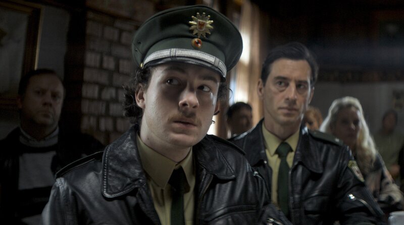 Krewlow in den 190ern: Der junge Polizist Roland Voit (Maximilian Ehrenreich) und Polizeichef Justus Voit (Robert Glatzeder, 2. v. re.) – Bild: ARD Degeto/​Surreal Dogs GmbH/​CBS Studios