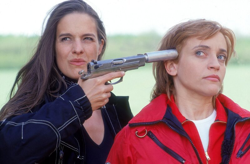 Andrea Matucini (Helen Zellweger, li.) hat gerade das gestohlene Geld umgeladen und wollte sich auf die Flucht machen als Dr. Thaler (Roswitha Meyer) sie überrascht und versucht daran zu hindern. Doch schnell hat Andrea sie in ihrer Gewalt und bedroht sie mit einer Pistole. – Bild: RTLplus /​ Miguel Dieterric