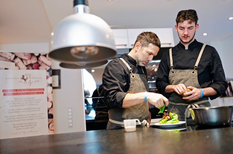 Konzentriert bei der Arbeit: Ausbilder Manuel (l) mit Koch-Azubi Erik. – Bild: WDR/​i&u Studios/​Ben Knabe
