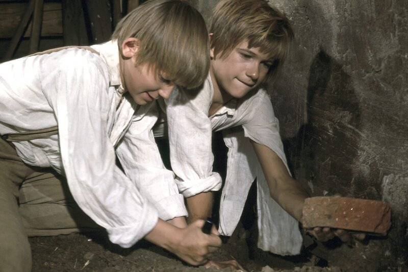 Nicht ganz geheuer ist es Tom (Roland Demongeot, l.) und Huck (Marc di Napoli) bei ihrem nächtlichen Abenteuer. Sie sind in die Scheune neben Muff Potters Gefängnis eingedrungen und suchen im Schein einer Laterne den günstigsten Platz für einen Durchbruch in den Nebenraum. – Bild: Georg Meyer-Hanno /​ ZDF