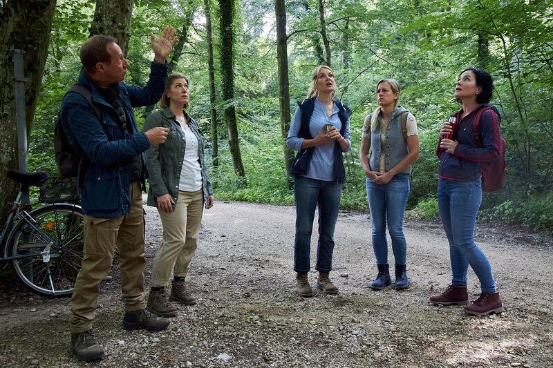 Walter Rübesam (Mike Maas, l.), Steffi Kurtz (Ines Honsel, 2.v.l.), Judith Färber (Nina Brandhoff, M.) und Rosi Mitterer (Simona Mai, 2.v.r.) vom Verein der „Rosenheimer Waldfreunde“ erklären Frau Stockl (Marisa Burger, r.), was beim „Waldbaden“ zu beachten ist. – Bild: Bojan Ritan /​ ZDF