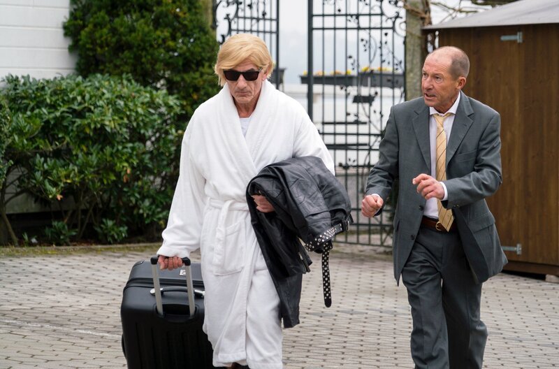 Klinikchef Konrad Weiss (Michael Lesch, r.) laufen bereits die ersten Gäste weg (Komparse, l.). – Bild: ARD/​TMG/​Arvid Uhlig