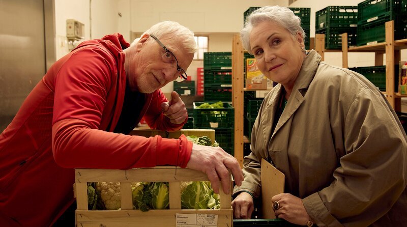 Herr Kurtz (Ernst Stötzner, li.) zeigt Anna (Katerina Jacob, re.) stolz seinen neuen Nebenjob bei der Tafel. – Bild: ARD Degeto Film/​Kai Schulz