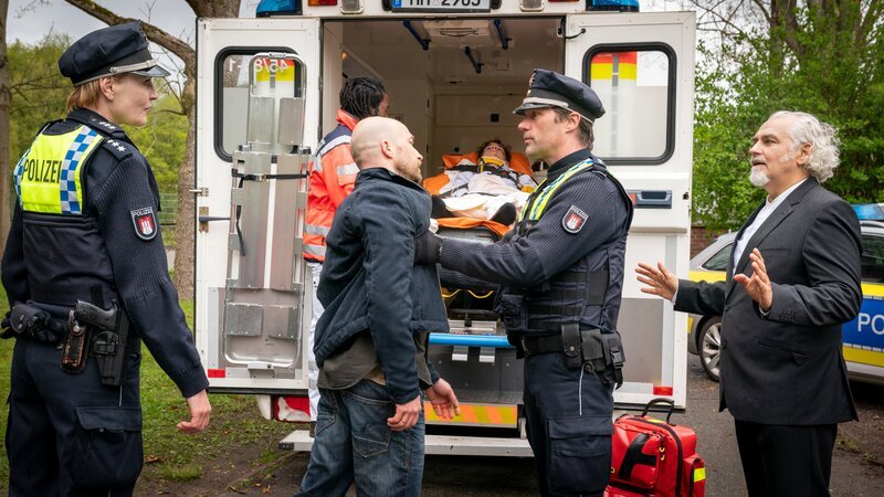 Melanie (Sanna Englund, l.) und Mattes (Matthias Schloo, 2.v.r.) halten Arnd Riggers (Johannes Benecke, 2.v.l.) in Schach, der Gideon Frey (Hansa Czypionka, r.) dafür verantwortlich macht, dass sein Sohn Tommy (Paul Ahrens, M.) von einem Balkon gesprungen ist. – Bild: Boris Laewen /​ ZDF