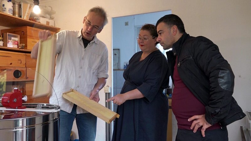 Andreas (li.) testet seine neue Honigschleuder. Margret und Späti-Besitzer Mehmet schauen ihrem Parzellennachbarn dabei interessiert über die Schulter – Bild: RTLZWEI