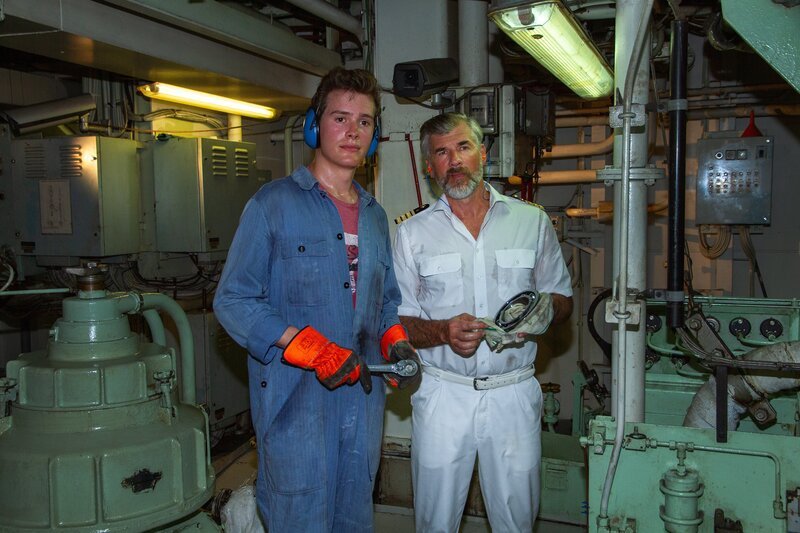 Eric Sommer (Lucas Bauer, l.) hilft Staff-Kapitän Martin Grimm (Daniel Morgenroth, r.), den Motor des Schiffes zu überprüfen, um seine Überfahrt zu bezahlen. – Bild: ZDF und Dirk Bartling