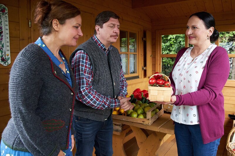 Frau Grasegger (Ursula Maria Burkhart, r.) hat in ihrem Schrebergarten zu viel Obst und Gemüse angebaut, sodass sie ihren Nachbarn Annegret (Eva Wittenzellner, l.) und Hartmut Nerlinger (Georg Veitl, M.) einen Teil davon schenkt. – Bild: Bojan Ritan /​ ZDF