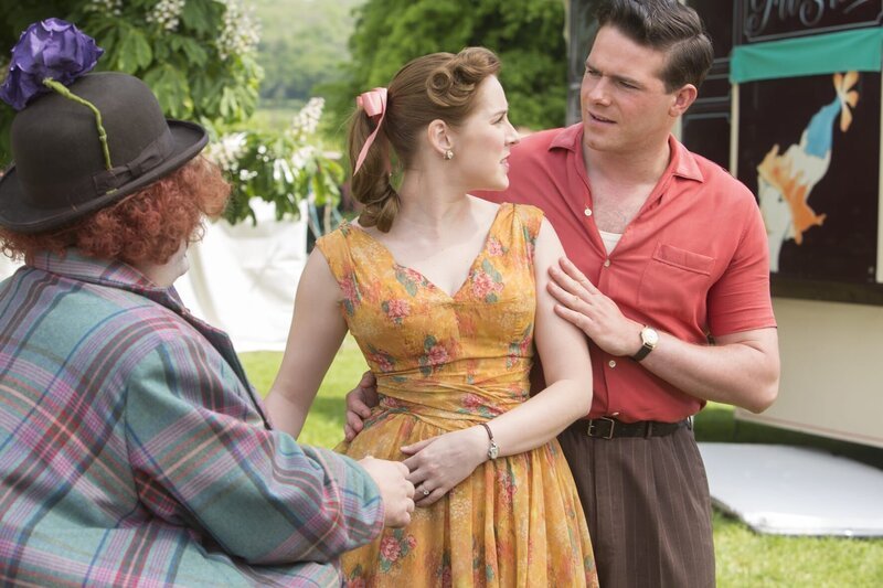 Nicholas (Joe Layton, r.) fragt seine Verlobte Laura (Justine Cain, m.) was Clown Smythe (Sevan Stephan, l.) von ihr will. Diesem hatte Laura im Scherz versprochen, dass sie ihn heiratet. – Bild: Gary Moyes