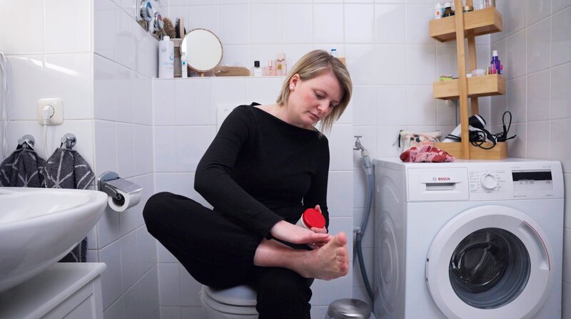 Ohne Vaseline geht nichts: Täglich cremt Pia O. ihre Füße ein, damit sie ihren Alltag irgendwie bewältigen kann. So stark wird sie von der Psoriasis-Arthritis, der rheumatischen Schuppenflechte, eingeschränkt. – Bild: NDR/​nonfictionplanet/​Hubert Marady